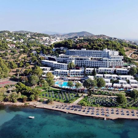 Hotel Dolce By Wyndham Athens Attica Riviera Vravrona Exterior foto The image shows a large hotel complex situated near a beach. It's located on a hillside, surrounded by greenery and trees. The hotel features multiple levels with modern architecture, balconies, and a swimming pool area. In front of the hotel, there'