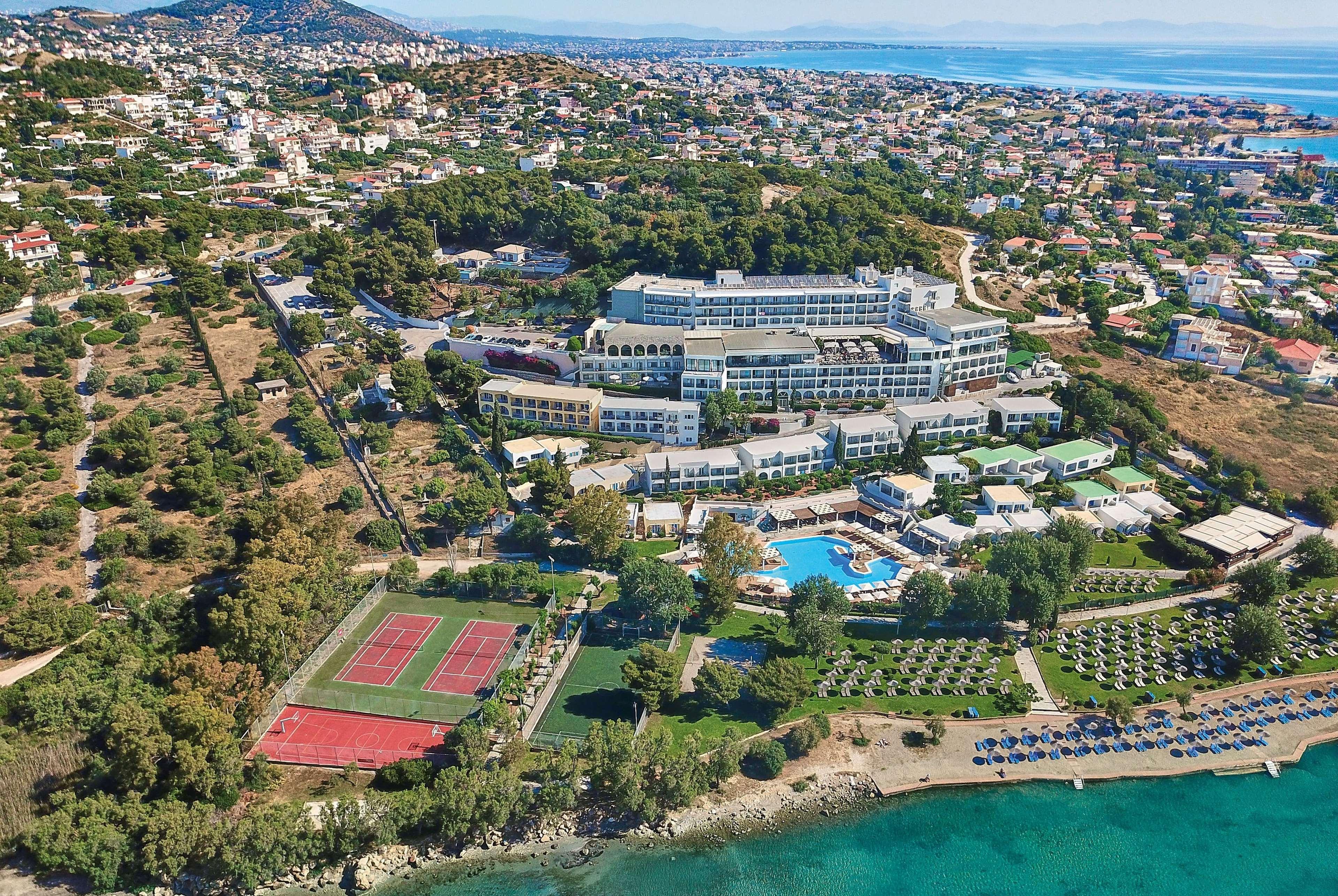 Hotel Dolce By Wyndham Athens Attica Riviera Vravrona Exterior foto The photo shows an aerial view of a resort or hotel complex situated near the coast. The building appears to be large, with multiple levels and several balconies. Surrounding the hotel are green landscaped areas, including gardens and perhaps a pool.